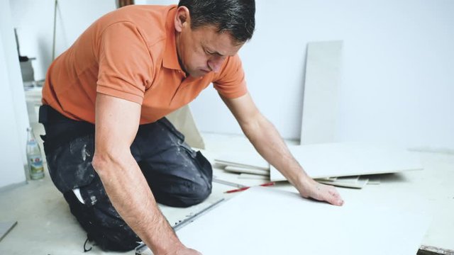 Handwerker schneidet grosse fliesen mit Fliesenschneider in einem neubau haus 4k Video in zeitlupe