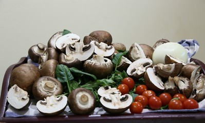 Still life from products: mushrooms, spinach, tomatoes small and large, onions side view