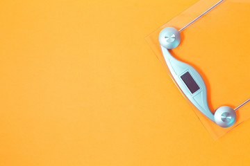 Empty glass floor weighing scale on saffron yellow background in flat lay with copy space. Weight management and healthy lifestyle sport concept