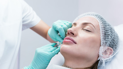 The young beautician doctor preparing to making injection in female lips. The doctor cosmetologist...
