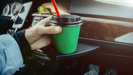 green cardboard cup of coffee in the car in the hands. drink on the go.