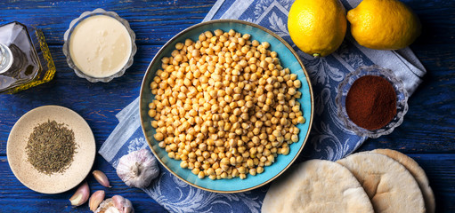 Chickpeas and various ingredients on a dark blue wooden background