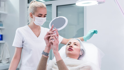 Obraz premium The young beautician doctor preparing to making injection in female lips. The doctor cosmetologist makes lip augmentation procedure.