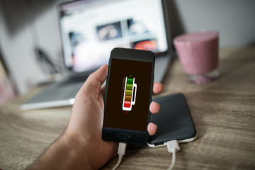 Man holding mobile phone in his hand that is charging with power bank