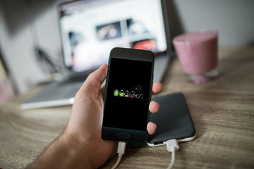 Man holding mobile phone in his hand that is charging with power bank