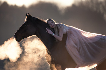Frau liegt im Sonnenaufgang romantisch auf dem Pferdehals