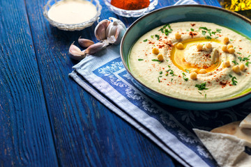 Chickpea hummus and various ingredients on a dark blue wooden background