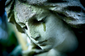  Close up ancient statue of crying angel with tears in face as symbol of death and end of human...