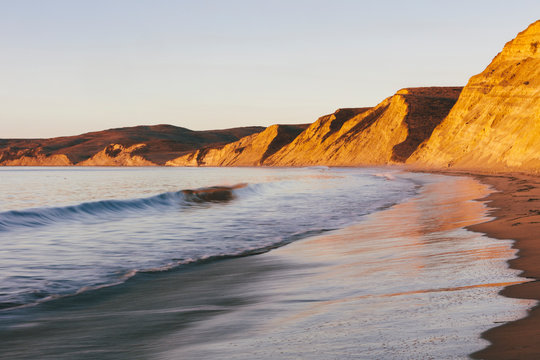 Steep cliffs and beach with surf at dawn,Cliffs and surf at Drakes Beach, dawn, Pt. Reyes National Seashore, California