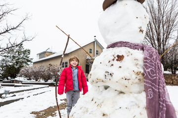 A six year old boy building a snowman