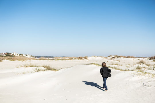 A six year old boy walking over sand dunes in open space. ,St Simon's Island