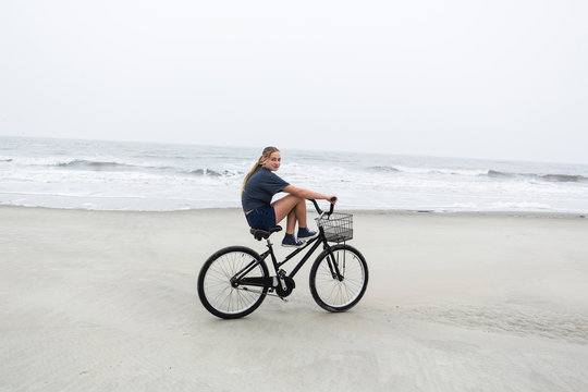 teen girl biking on sandy beach by the ocean, St. Simon's Island, Georgia,St Simon's Island