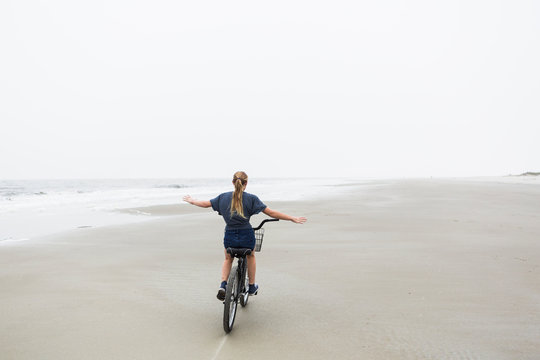 teen girl biking on sandy beach by the ocean, St. Simon's Island, Georgia,St Simon's Island