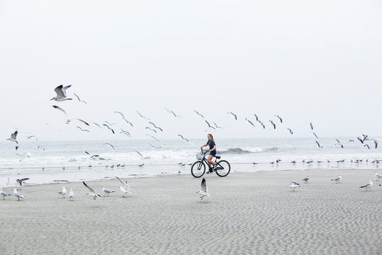 teen girl biking on sandy beach by the ocean, St. Simon's Island, Georgia,St Simon's Island