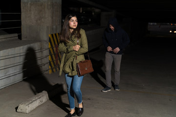 Criminal Walking Behind Unsuspecting Young Woman In Dark