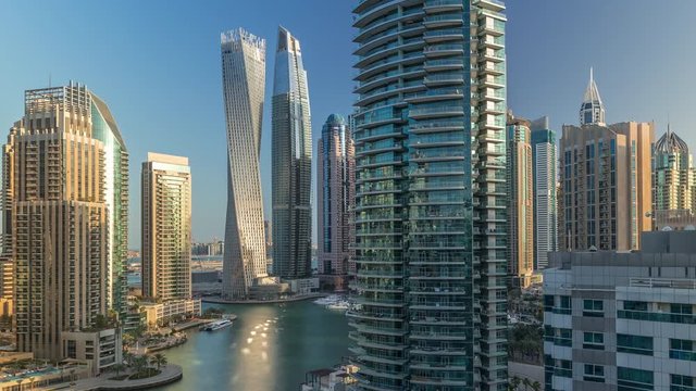 Aerial view of Dubai Marina residential and office skyscrapers with waterfront timelapse. Morning after sunrise with shadows moving fast. Sun reflected from glass. Floating boats and yachts