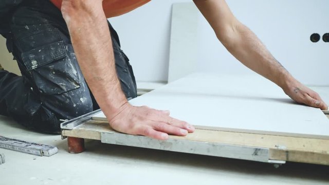 Handwerker schneidet grosse fliesen mit Fliesenschneider in einem neubau haus 4k Video in zeitlupe