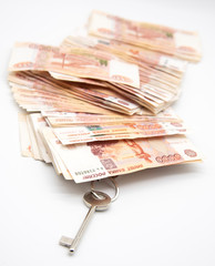 The key to the apartment and five thousand ruble bills on a light background. Symbol of the accumulation of finance and home improvement