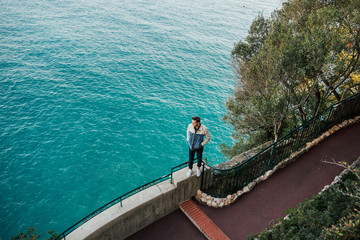 Young man standing on the stone near Mediterranean sea with azure water in Monaco. Travel. He stands and admire azure sea on background.