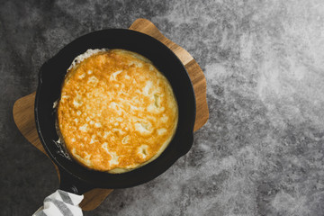 Omelette in black skillet pan, dark food photo. Top view of fresh breakfast. Copy space.