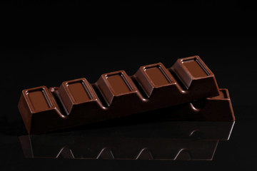 Chocolate with filling on a black background with reflection.