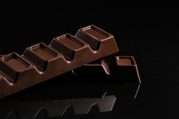 Milk chocolate on a black background. Close-up.
