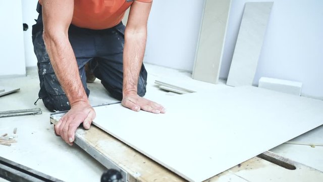 Handwerker schneidet grosse fliesen mit Fliesenschneider in einem neubau haus 4k Video in zeitlupe