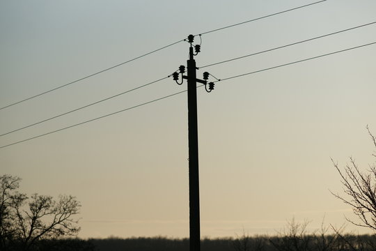 Electric pillar with wires in blue sky and forest background
