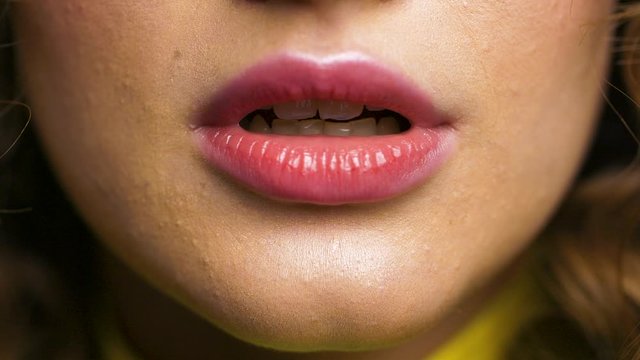 Close up Video shot of Woman&rsquo;s Face with nice plump Pink lips having Glamorous lipstick on. Woman with attractive Appearance and trendy makeup. Having brunette Hair and beige tone cream. White teeth.