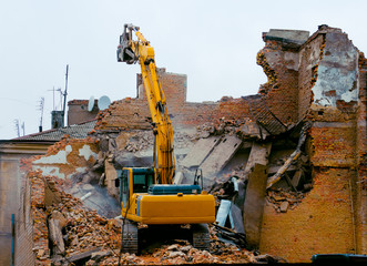 A bulldozer destroys an old building. The concept of the demolition of a building under construction of a new house. Dismantling an old house