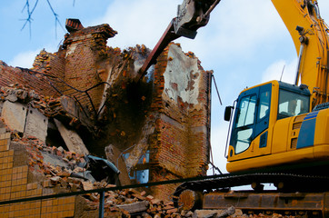 Fototapeta premium A bulldozer destroys an old building. The concept of the demolition of a building under construction of a new house. Dismantling an old house