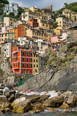 Fototapeta na wymiar Riomaggiore, Cinque Terre, Italy - August 17, 2019: Village by the sea bay, colorful houses on the rocky coast. The protected area of â€‹â€‹the mountains. A popular resort in Europe