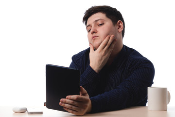 Young guy in a blue shirt use a tablet as a mirror office worker, business. on white background. isolate. copy space