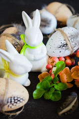 Easter background with decorative Easter eggs, rabbits and blossoming spring branch.