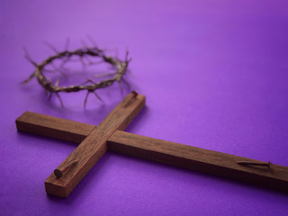 Good Friday, Palm Sunday, Ash Wednesday, Lent Season and Holy Week concept.  A Christian cross, three rusty nails and a woven crown of thorns on purple background.