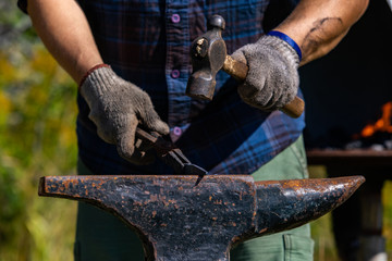 A close up selective focus shot of a traditional blacksmith, using an anvil and hammer to work...