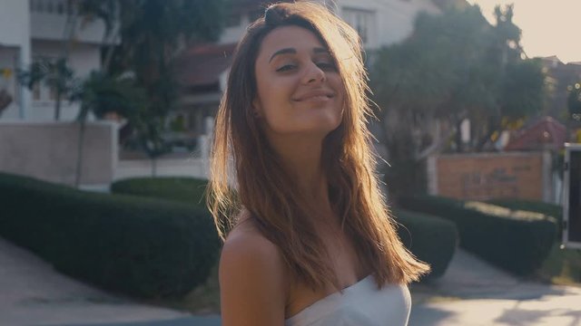 Attractive girl with bare shoulders posing while looking at the camera. She is convicted, moves and straightens her hair 4k