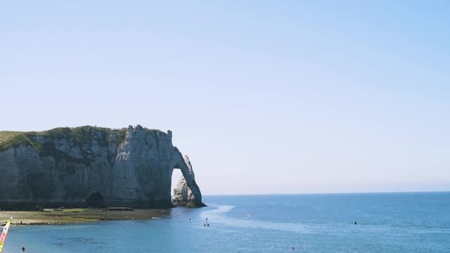 Beautiful landscape with turquoise sea, yellow steep cliff and two sea gulls fly over the sea in the summertime. Action. Summer travel concept, birds flying on blue sky background.