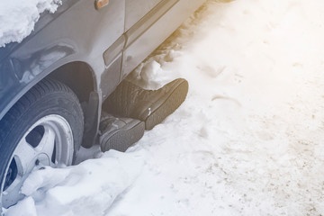protruding shoes and feet from under the car after an accident in the snow - obrazy, fototapety, plakaty