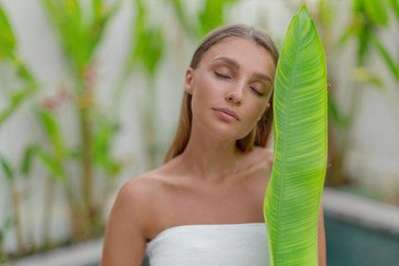 Portrait of a beautiful young girl with a green leaf. Spa treatments.