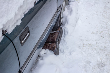 Fototapeta protruding shoes and feet from under the car after an accident in the snow obraz