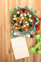 Authentic fresh salad in a stone cup with dumbbells excercise equipment, measuring tape on table. healthy lifestyles, good health Concept with fresh ingredients