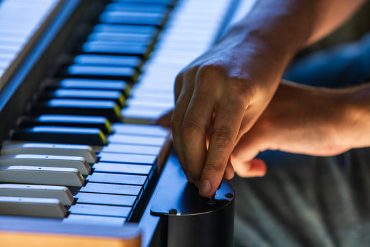 A Close Up Selective Focus View Of A Man Playing An Electronic Keyboard During A Music Set On Stage At A Daytime Festival, Copy Space To Sides