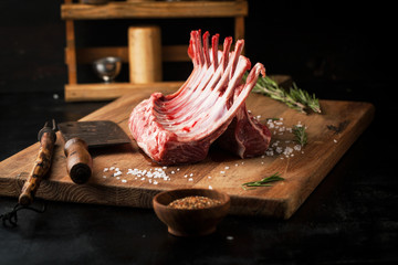 Raw rack of lamb with spices on a cutting board - 324365697