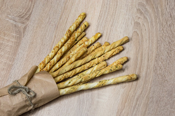 Italian grissini breadsticks in craft paper package on wooden table background 