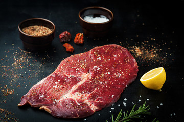Raw piece of beef with spices, salt and rosemary