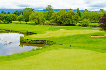 Obraz premium Golf course with gorgeous green and pond.
