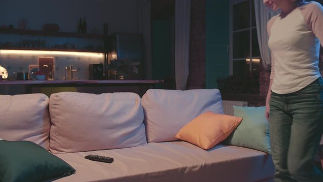 Young woman sitting on couch in cozy living room watching TV