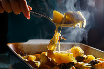 Girl picks up a spoonful of baked potatoes with mushrooms and cheese