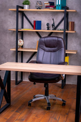  working place in the office leather chair and wooden table on the background of a shelf with books